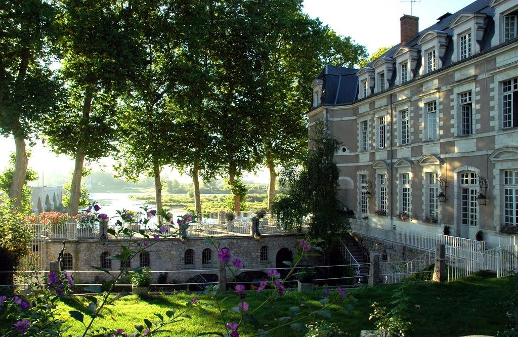 Façade en pierre du Grand Hôtel de l'Abbaye et son jardin arboré
