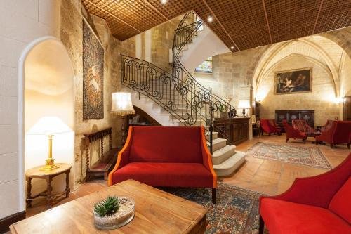 Salon voûté en pierre de l'Hôtel des Augustins, escalier en fer forgé et canapés rouges