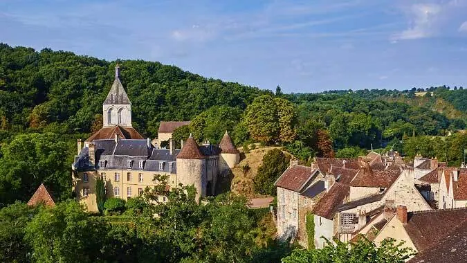 Village de Saint-Amand-Montrond dans un vallon boisé, église et toits de tuiles